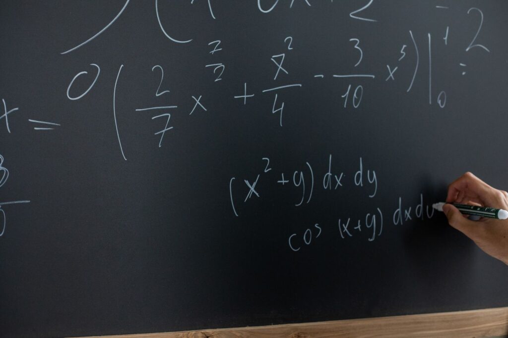 Hand writing calculus integrals and equations on a blackboard