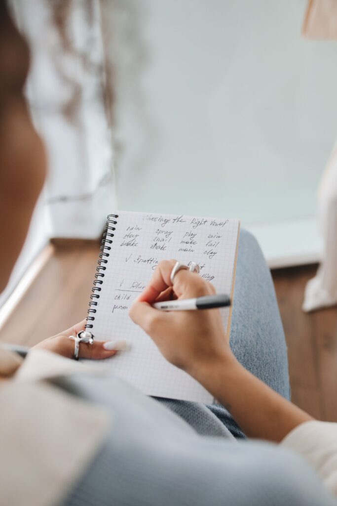 Close-up of a person handwriting notes in a spiral notebook